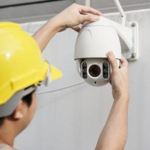 close up male technician fixing cctv camera-wall